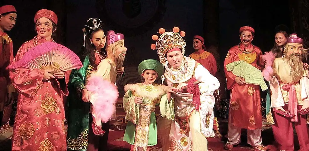 Famly performing with traditional Vietnamese opera troupe at a historic theater in Hanoi