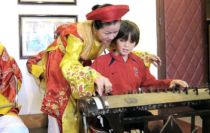 Child learning to play the traditional Vietnamese instrument, dan bau.